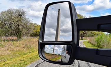 The San Jacinto Monument shown in a van's rear view mirror